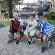 Stanovalec in otrok skupaj igrata na harmoniko
